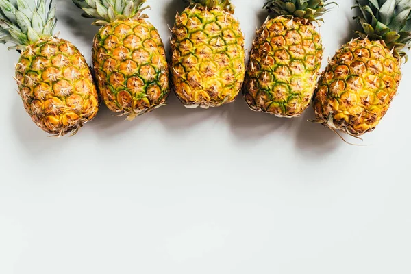 Vista superior de piñas frescas maduras con hojas verdes sobre fondo blanco — Stock Photo