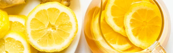 Top view of hot tea in teapot near lemon on plate on white background, panoramic shot — Stock Photo