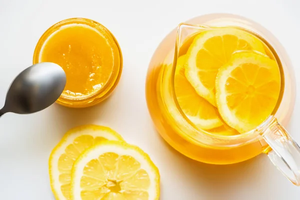 Vista dall'alto di tè caldo con limone vicino miele con cucchiaio su sfondo bianco — Foto stock