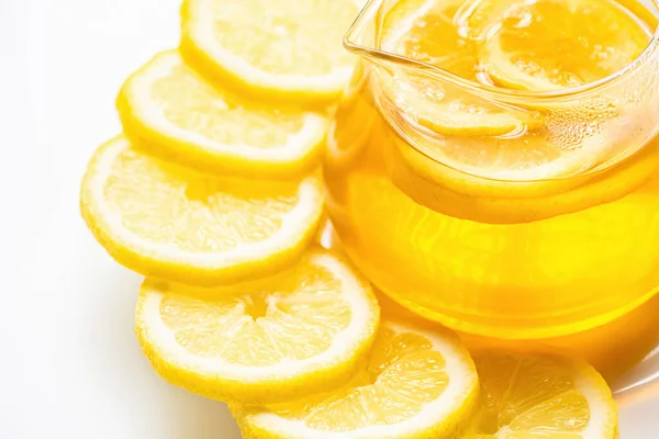 Vue rapprochée du thé chaud dans une théière en verre avec des tranches de citron sur fond blanc — Photo de stock