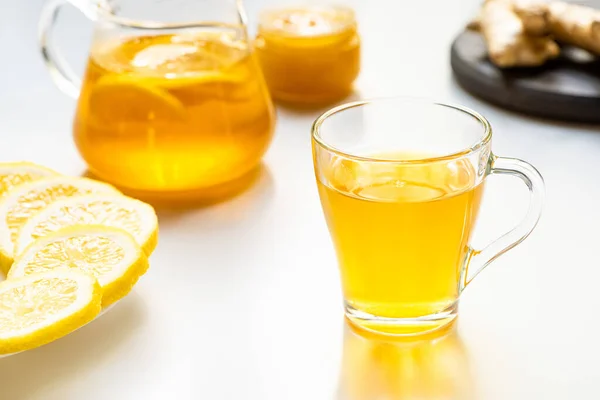 Foyer sélectif de thé chaud dans une tasse en verre avec des tranches de citron sur fond blanc — Photo de stock