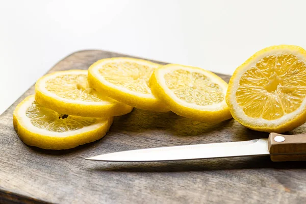 Enfoque selectivo de limón caliente sobre tabla de cortar de madera con cuchillo sobre fondo blanco - foto de stock