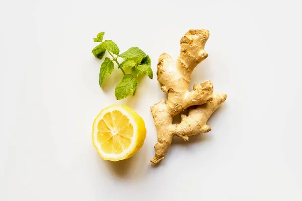 Vue du dessus de la racine de gingembre, citron et menthe sur fond blanc — Photo de stock