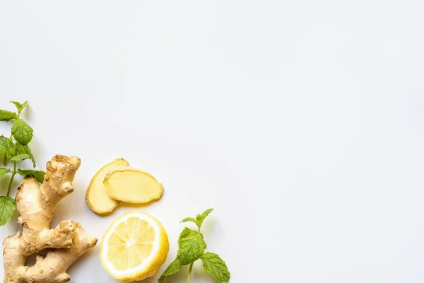Вид сверху на корень имбиря, лимон и мяту на белом фоне — стоковое фото