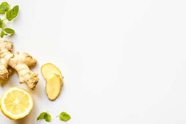 Vista superior de raiz de gengibre, limão e folhas de hortelã no fundo branco — Fotografia de Stock
