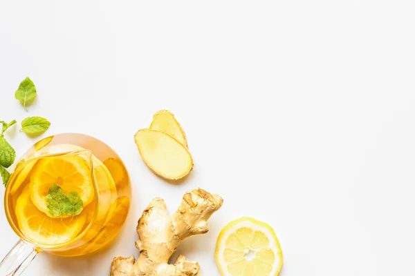 Top view of hot tea near ginger root, lemon and mint on white background — Stock Photo