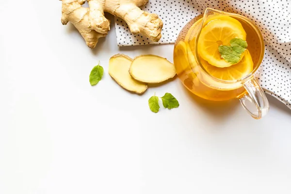 Vue du dessus du thé chaud sur serviette près de la racine de gingembre, citron et menthe sur fond blanc — Photo de stock