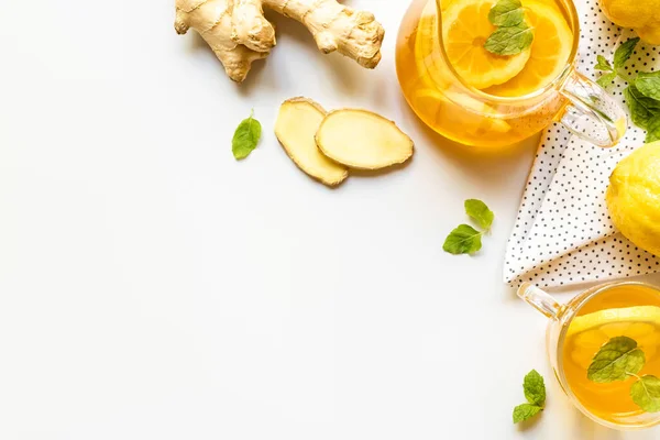 Top view of hot tea on napkin near ginger root, lemon and mint on white background — Stock Photo