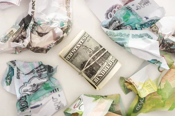 Vista dall'alto del rotolo di contante con dollari vicino alle banconote in rublo spiegazzate isolate su bianco — Foto stock