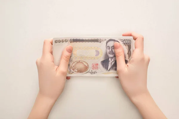 KYIV, UKRAINE - MARCH 25, 2020: cropped view of woman holding japanese yen banknote isolated on white — Stock Photo