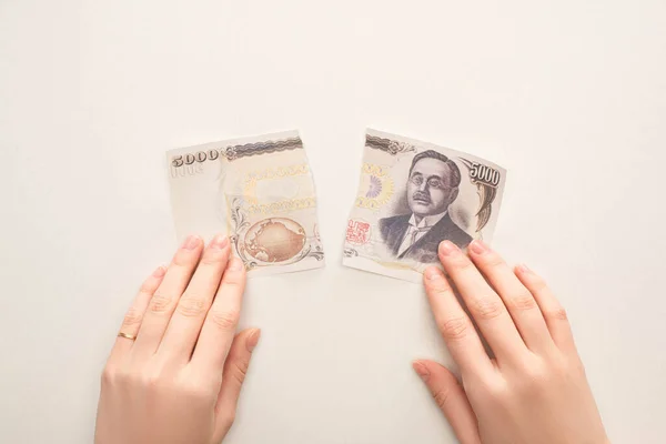 KYIV, UKRAINE - 25 MARS 2020 : vue de dessus d'une femme touchant un billet en yen japonais déchiré isolé sur blanc — Photo de stock