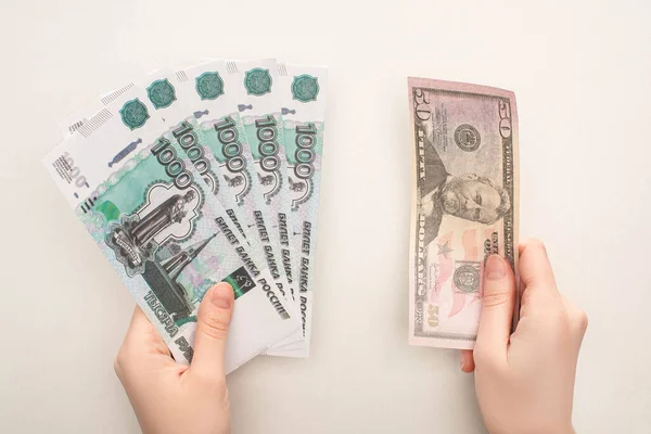 KYIV, UKRAINE - MARCH 25, 2020: top view of woman holding russian rubles and $banknote isolated on white — стокове фото