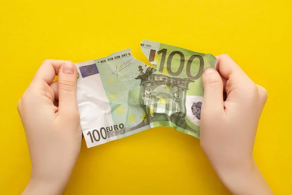 QUIIV, UCRÂNIA - MARÇO 25, 2020: visão cortada de uma mulher a rasgar uma nota de euro amassada isolada a amarelo — Fotografia de Stock