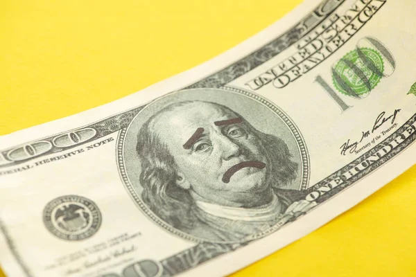 Primer plano del billete de dólar con triste dibujo de la cara aislado en amarillo - foto de stock