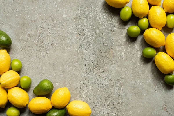 Vista dall'alto di avocado colorato, lime e limoni su una superficie di cemento grigio — Foto stock