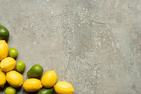 Draufsicht auf bunte Limetten, Avocado und Zitronen auf grauer Betonoberfläche — Stockfoto