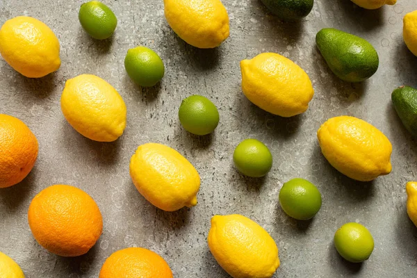 На сірій бетонній поверхні лежали барвисті лімузини, апельсини, авокадо та лимони. — стокове фото