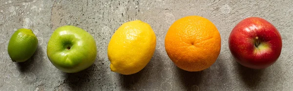 Top view of tasty colorful fruits on grey concrete surface, panoramic shot — Stock Photo