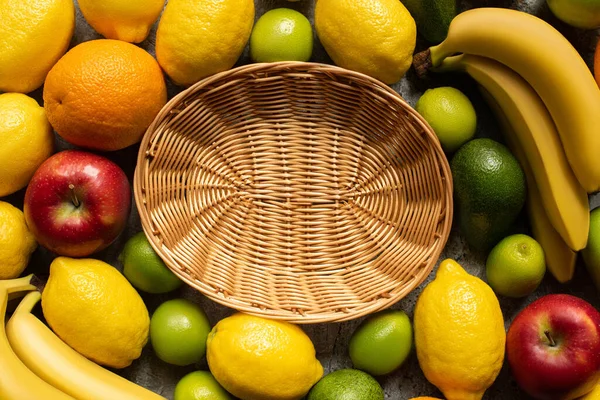 Top view of tasty colorful fruits around wicker basket — Stock Photo