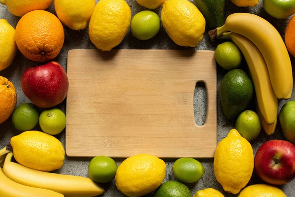 Vista superior de sabrosas frutas de colores y tabla de cortar de madera - foto de stock