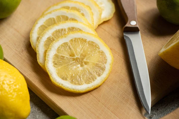 Vue rapprochée du citron tranché sur planche à découper en bois avec couteau — Photo de stock