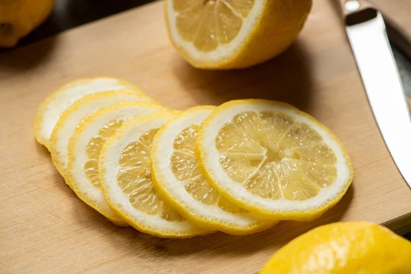 Vue rapprochée du citron tranché sur planche à découper en bois avec couteau — Photo de stock