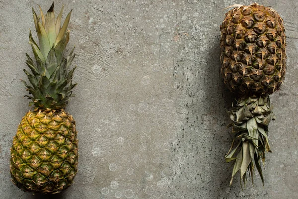 Top view of ripe pineapples on grey concrete surface with copy space — Stock Photo