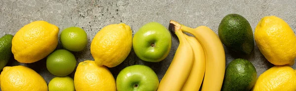 Vue de dessus de l'avocat coloré, citrons verts et citrons sur la surface en béton gris, vue panoramique — Photo de stock