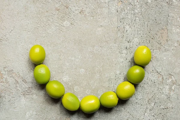 Vue de dessus des citrons verts sur la surface en béton gris — Photo de stock