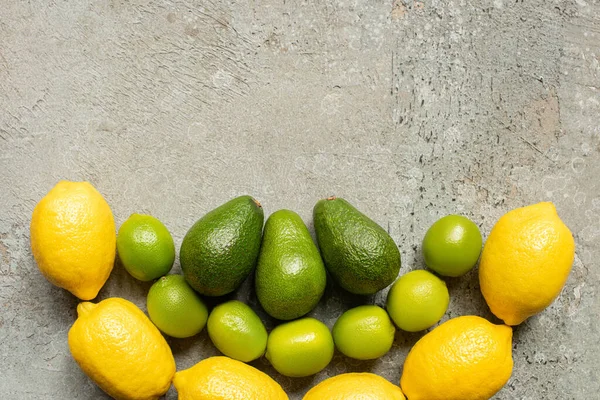 Top view of colorful avocado, limes and lemons on grey concrete surface — Stock Photo