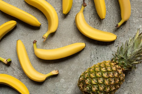 Vista superior de deliciosas bananas coloridas e abacaxi na superfície de concreto cinza — Fotografia de Stock