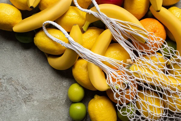 Vue de dessus des fruits colorés et sac à ficelle sur la surface en béton gris — Photo de stock