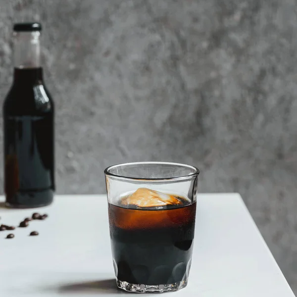 Selective focus of cold brew coffee with ice in glass on white table — Stock Photo