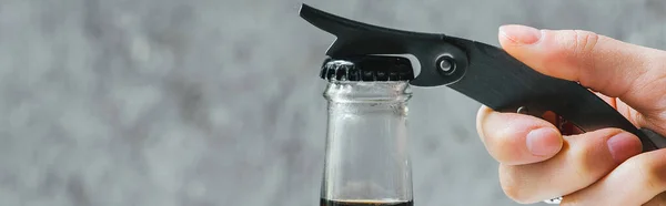 Cropped view of woman opening cold brew coffee in bottle with opener, panoramic shot — Stock Photo