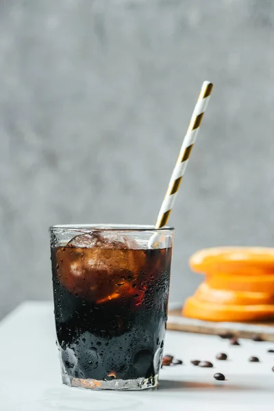 Enfoque selectivo de café de cerveza fría con hielo y beber paja en la mesa blanca - foto de stock