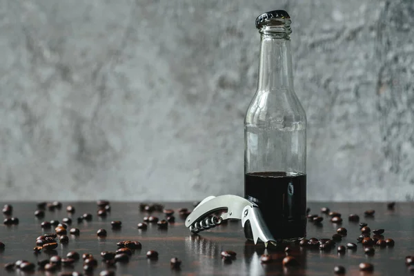 Caffè freddo in bottiglia vicino all'apribottiglie e ai chicchi di caffè — Foto stock