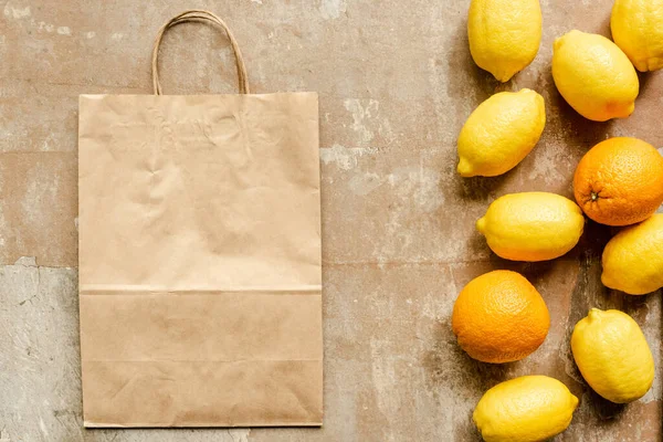 Top view of lemons and oranges near paper bag on weathered surface — Stock Photo