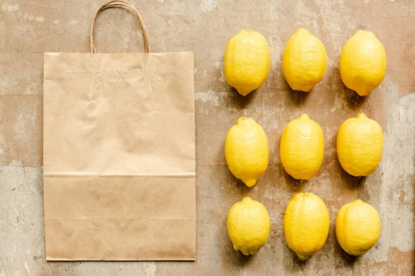 Flat lay with lemons near paper bag on weathered surface — Stock Photo