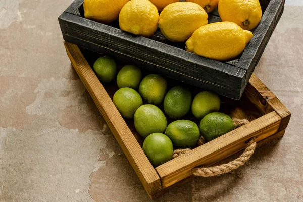 Limões maduros e limas em caixas de madeira na superfície intemperizada — Fotografia de Stock