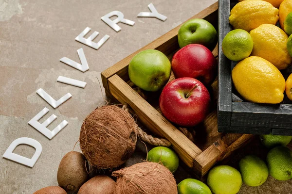 Ripe fresh fruits in wooden boxes near word delivery on weathered surface — Stock Photo