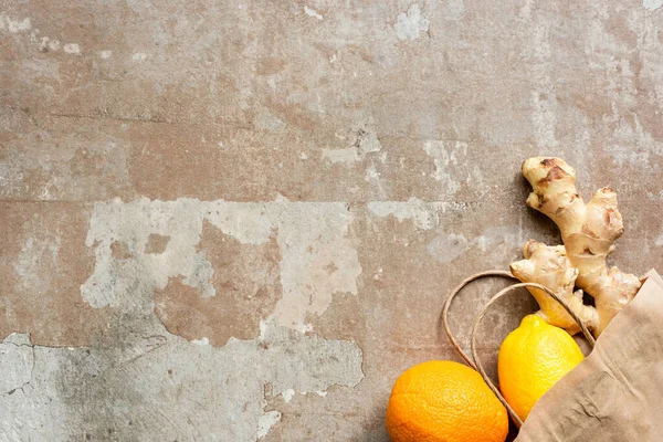 Ansicht von Zitronen-, Orangen- und Ingwerwurzel in Papiertüte auf verwitterter Oberfläche — Stockfoto