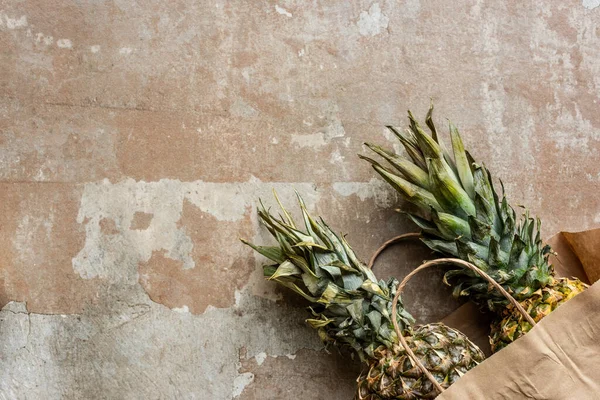 Top view of ripe pineapples in paper bag on weathered surface — Stock Photo