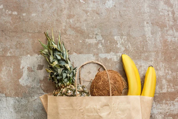 Top view of tropical fresh fruits in paper bag on weathered surface — Stock Photo