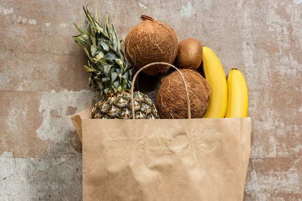 Top view of tropical fresh fruits in paper bag on weathered surface — Stock Photo