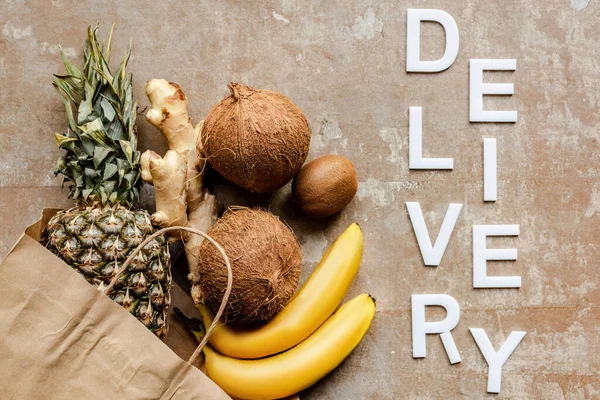 Vista dall'alto di frutta fresca tropicale e radice di zenzero in sacchetto di carta su superficie intemperie con consegna parola — Foto stock