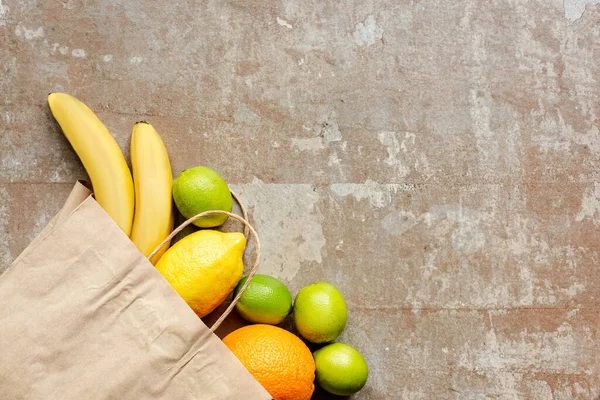 Vue du dessus du sac en papier avec des fruits frais sur la surface altérée — Photo de stock