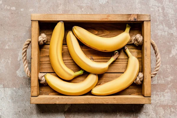 Top view of ripe bananas in wooden box on weathered surface — Stock Photo