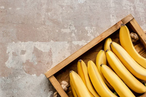 Вид зверху на стиглі банани в дерев'яній коробці на вивітреній поверхні — стокове фото