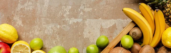 Top view of ripe summer fruits in wooden box and on weathered beige surface, panoramic crop — Stock Photo