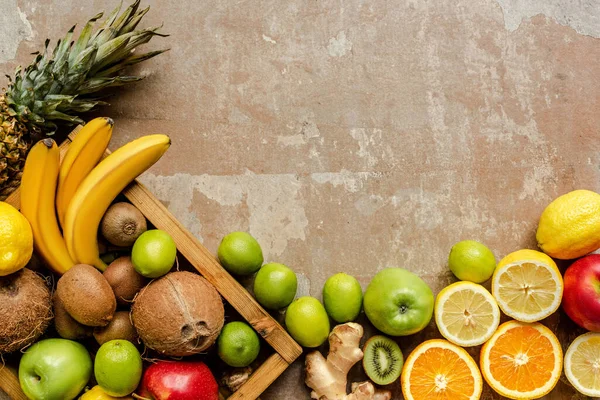 Top view of ripe summer fruits in wooden box and on weathered beige surface — Stock Photo